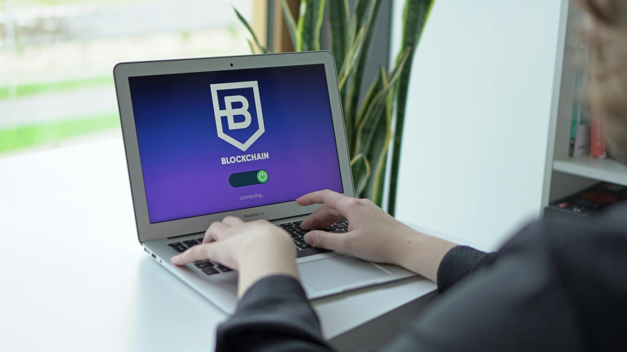 Close-up of hands on a laptop displaying a blockchain application, showcasing modern technology.